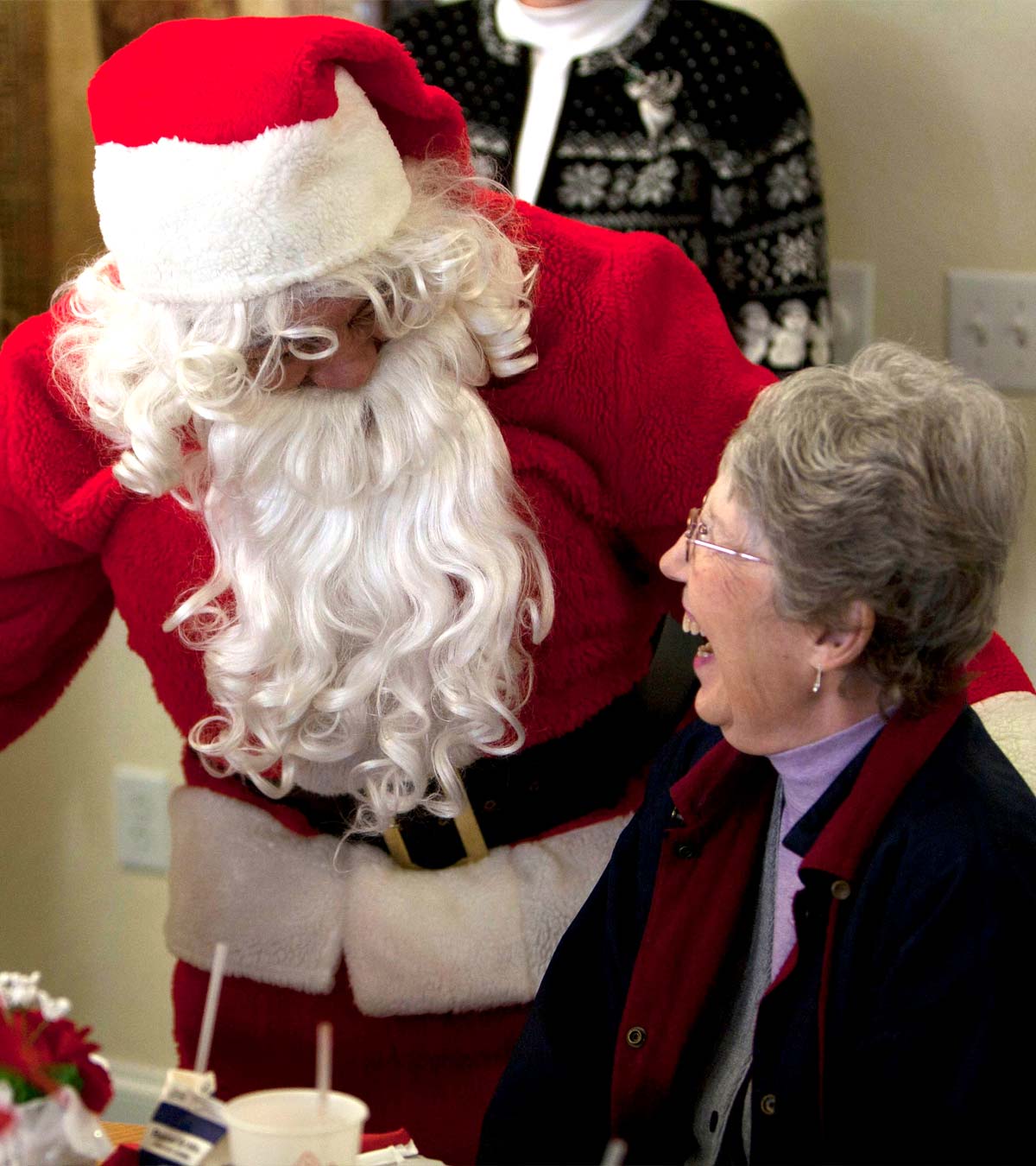 Santa greets two elated senior women seated at social event