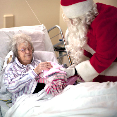santa delivers gifts of warm blankets to senior woman in bed